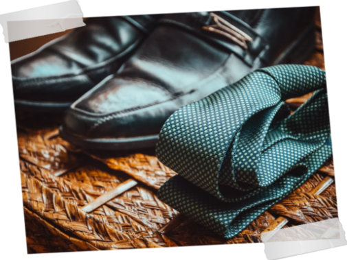 Pair of black dress shoes and a folded tie nearby